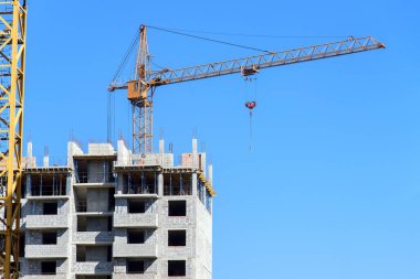 Mavi arka planda kule vinci olan modern apartman inşaatı sırasında