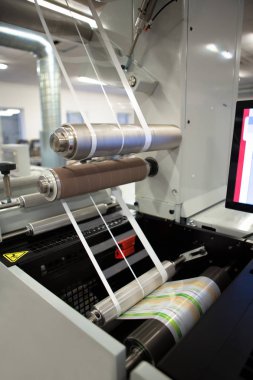 Yakın çekim shot flexo baskı makinesi üzerinde imalat etiket. Fotoğraf Detayı matris atık veya kaldırma fleksografik basında yapışkan malzemesinden trim.