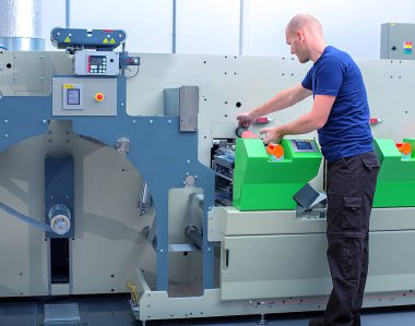 Polimer kabartma tabak ile baskı silindir tutan yazıcı operatör baskı makinesi yanında üzerinde sıkışmış. Yazdırma işlemi için hazırlık hatlı basın makine üzerinde gösterilen sahne.