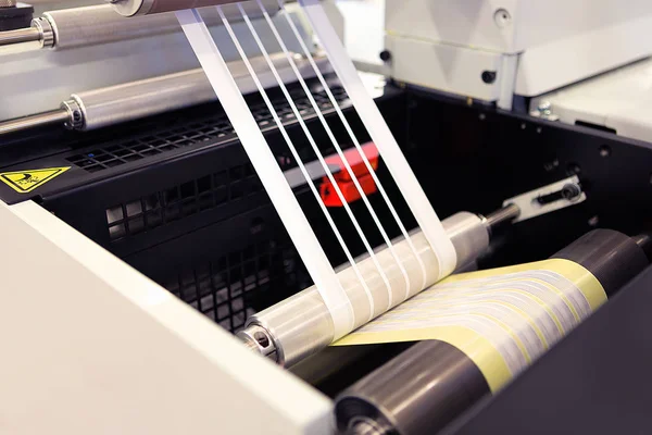 Yakın çekim shot flexo baskı makinesi üzerinde imalat etiket. Fotoğraf Detayı matris atık veya kaldırma fleksografik basında yapışkan malzemesinden trim.