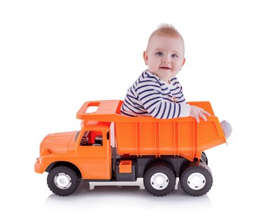 Bahşiş kamyonu oyuncaklarından oluşan açık kutuda oturan mutlu genç çocuk beyaz arka planda gölge yansıması ile izole edilmiş. Yeni yürümeye başlayan çocuk bir çöp kamyonunda oturuyor. Sevimli küçük çocuk kamyon kullanıyor..