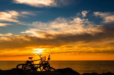 Şık bir deniz günbatımının arka planında bisiklet siluetleri