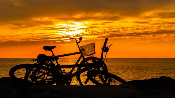 Silhouettes of bicycles on the background of a chic sea sunset — Stock Photo, Image