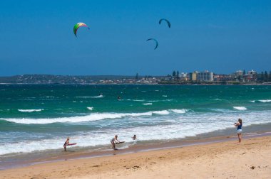 Sydney, Australia - November 9, 2014: People kite surfing and bodyboadring on Cronulla beach, Australia clipart