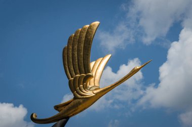 Arka planda mavi gökyüzüne karşı altın kuş heykeli