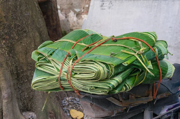 Folded palm leaves tied to scooter, bicycle with string