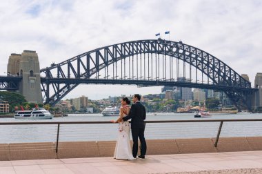 Sidney, Avustralya-10 Ekim 2014: gelin ve damat arka planda Sydney Harbour Köprüsü karşı poz Genç Asyalı düğün çift