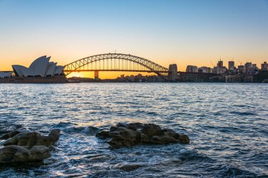 Gün batımında Sydney Harbour Köprüsü ve şehir manzarası