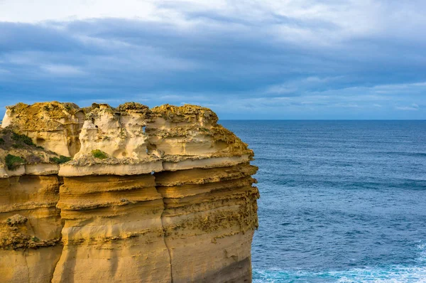 Arka planda mavi denize karşı kaba katmanlı kaya — Stok fotoğraf