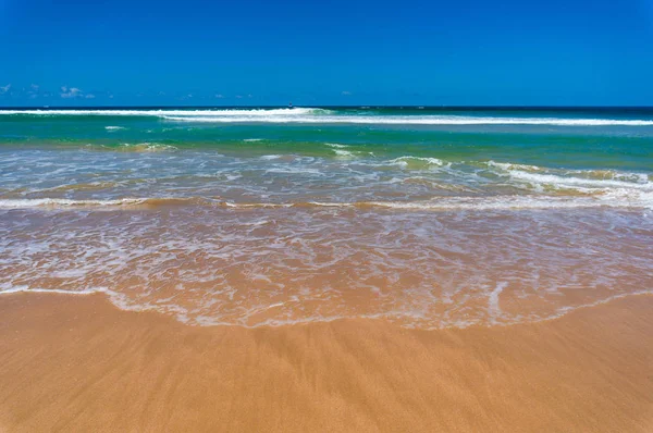 Natureza fundo de ondas na praia de areia e céu azul claro — Fotografia de Stock