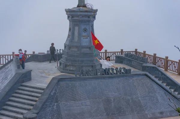 Turistas asiáticos con bandera vietnamita en la cumbre de la montaña de Fansipan — Foto de Stock