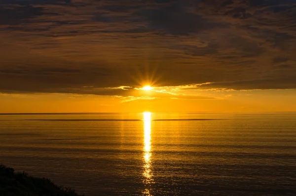 Espectacular puesta de sol sobre el mar con vivos colores dorados del agua y — Foto de Stock