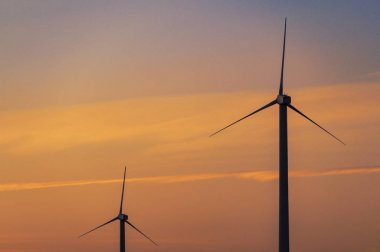 Yel değirmeni türbinleri, muhteşem gün batımı gökyüzüne karşı enerji jeneratörleri