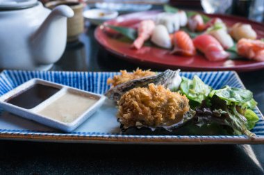 Yan tarafta soslar ve salata yaprakları ile ızgara istiridye