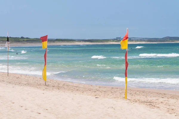 Red and yellow flags on patrolled beach indicating sfe to swim area