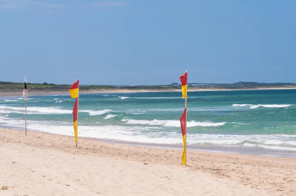 Banderas rojas y amarillas en la playa patrullada que indican que es seguro nadar — Foto de Stock