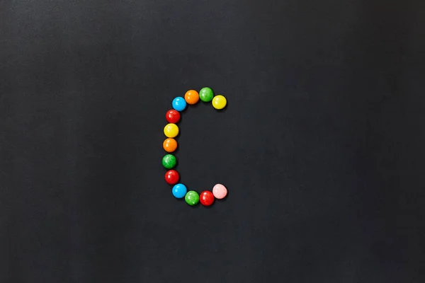 English Alphabet made of colored candies. The letter C.