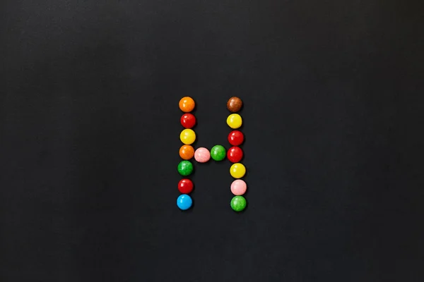 English Alphabet made of colored candies. The letter H.