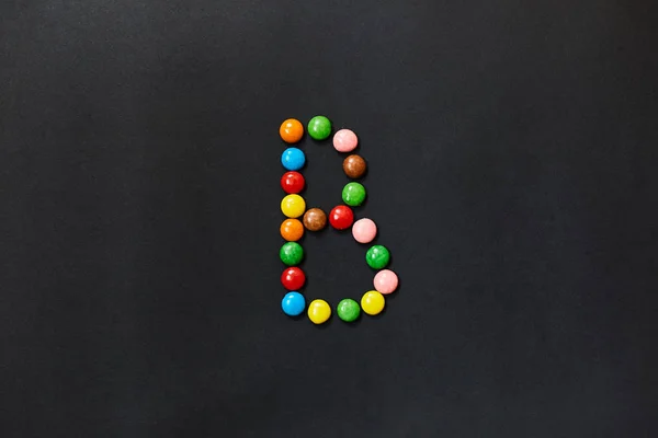 English Alphabet made of colored candies. The letter B.