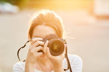 Günbatımında bir yaz parkta fotoğraf makinesinde resimleri alarak genç kız
