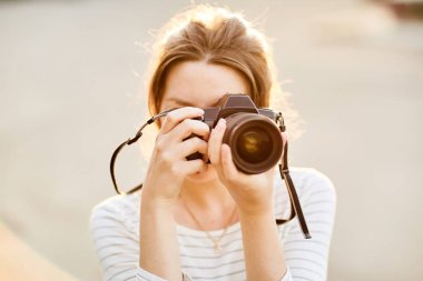 Günbatımında bir yaz parkta fotoğraf makinesinde resimleri alarak genç kız