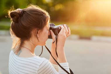 Günbatımında bir yaz parkta fotoğraf makinesinde resimleri alarak genç kız