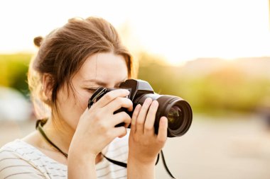 Günbatımında bir yaz parkta fotoğraf makinesinde resimleri alarak genç kız