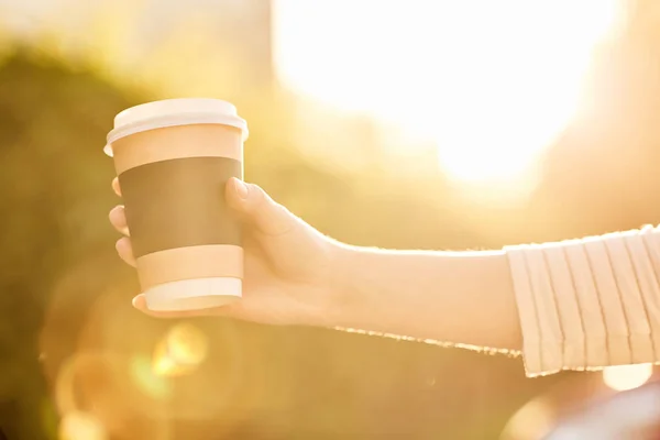 Niña sosteniendo papel taza con café caliente al atardecer — Foto de Stock