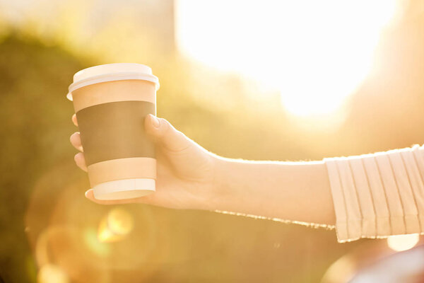 young girl holding paper Cup with hot coffee at sunset
