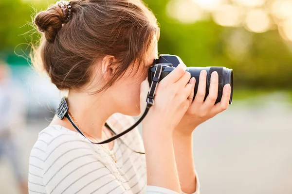 Günbatımında bir yaz parkta fotoğraf makinesinde resimleri alarak genç kız