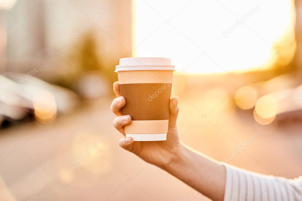 girl holding a glass of coffee at sunset