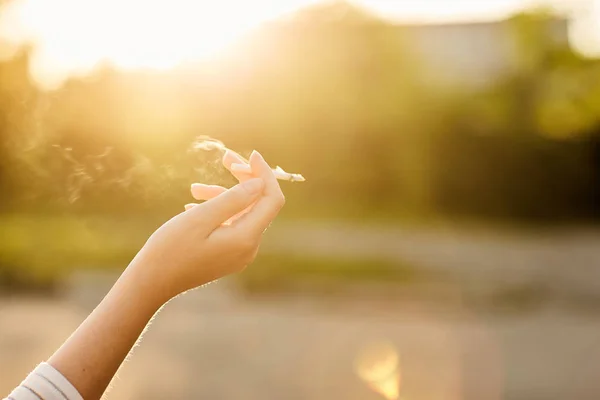 Chica sosteniendo un cigarrillo de fumar al atardecer — Foto de Stock