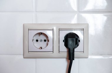 Electric black plug. Two sockets on a background of white tiles.  clipart