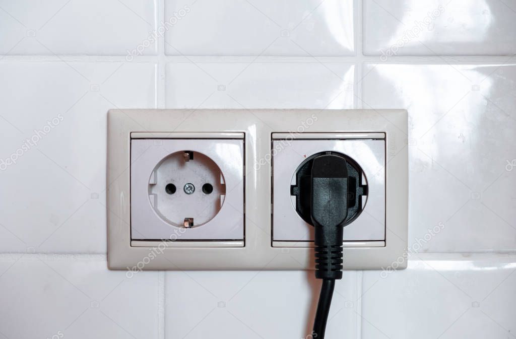 Electric black plug. Two sockets on a background of white tiles. 