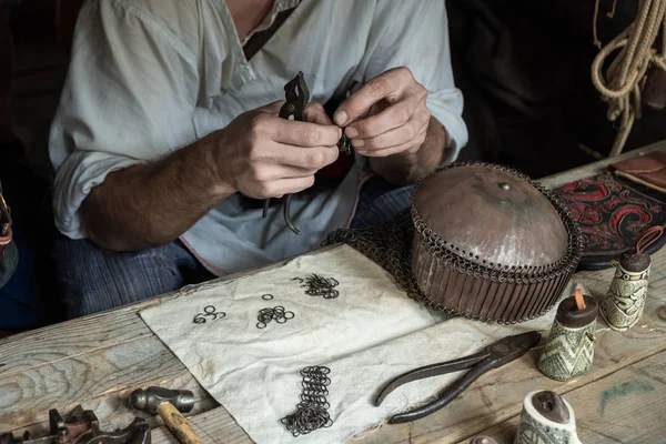 Maestro teje el correo de cadena de anillos de metal. Escamas de dragón . — Foto de Stock