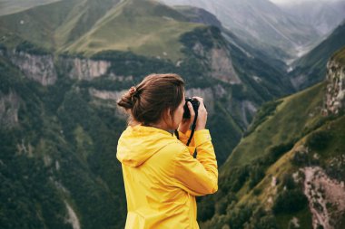 Genç bir kız sarı yağmurluk içinde dağlar fotoğraflar. Gürcistan. Yaz. Ağustos. Kız bir fotoğraf çekimi Dağı'nın yapım. 