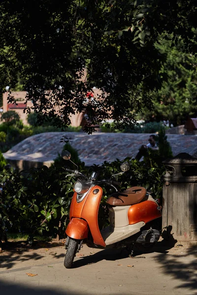 Оранжевый скутер в тени деревьев — стоковое фото