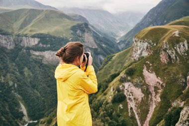 Genç bir kız sarı yağmurluk içinde dağlar fotoğraflar. Gürcistan. Yaz. Ağustos. Kız bir fotoğraf çekimi Dağı'nın yapım. 