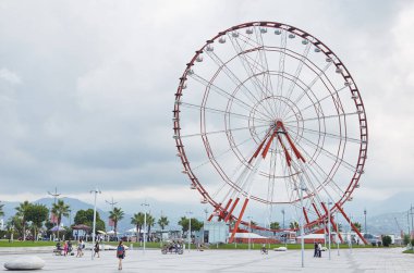 Kırmızı bir dönme dolap ve bir erkek ve bir kadın heykeli.