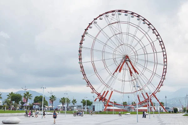 Ein rotes Riesenrad und eine Statue eines Mannes und einer Frau. — Stockfoto