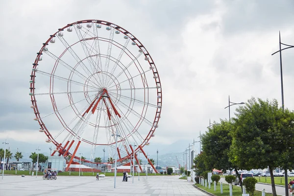 Ein rotes Riesenrad und eine Statue eines Mannes und einer Frau. — Stockfoto