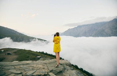 Genç bir kız sarı yağmurluk içinde dağlar fotoğraflar. Gürcistan. Yaz. Ağustos. Kız bir fotoğraf çekimi Dağı'nın yapım. 