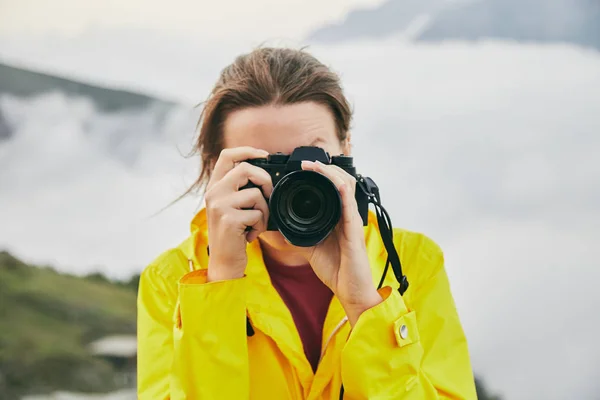 黄色のレインコートの少女写真の山。グルジア。夏。8 月。山の写真撮影を行う女の子. — ストック写真