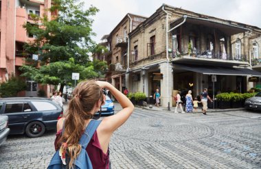 Genç bir kız eski binalar fotoğraflar. Turist kız eski şehir fotoğraflarını çeker.