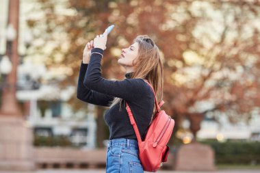 Genç bir kız ve şehir merkezinde bir fotoğrafı çeker. Telefonunuzda resimler alarak kız. Moskova Merkezi. 