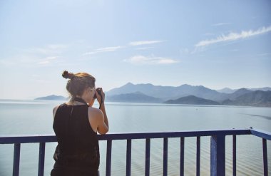 Genç bir kız göl fotoğraflarını. Turist İşkodra Gölü'nün bir fotoğrafı çeker. İşkodra Gölü. Milli park. Karadağ. 