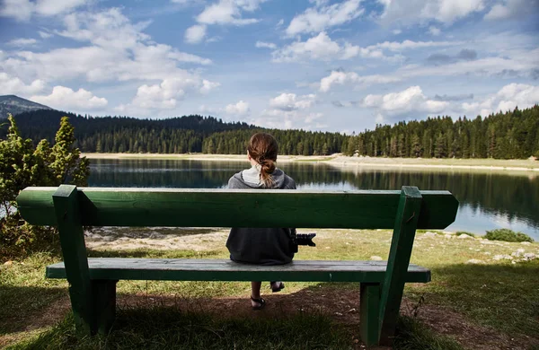 Ein junges Mädchen auf einer Bank sitzend. Schwarzsee. Durmitor-Nationalpark. Montenegro. — Stockfoto