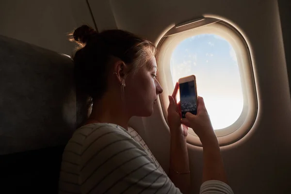 Holky z okna letadla. Dívka se vyfotí s jejím telefonem pohledu z okna — Stock fotografie