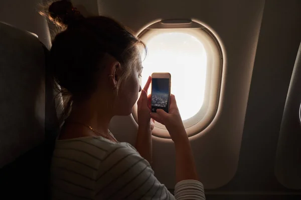 Holky z okna letadla. Dívka se vyfotí s jejím telefonem pohledu z okna — Stock fotografie