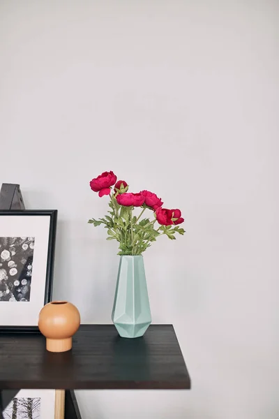 Red flower stands in a blue vase on the table.Interior detail. — Stock Photo, Image